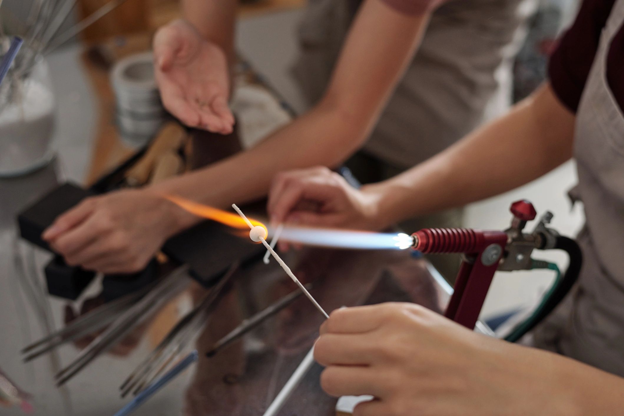 Hands shaping glass over a torch during scientific glassworking