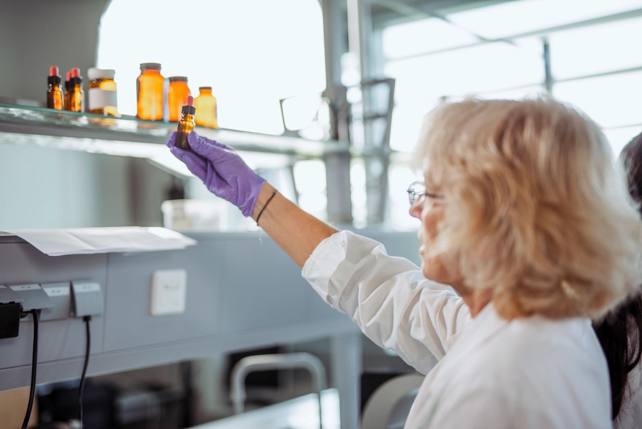 Lab professional reaching for an amber glass reagent bottle